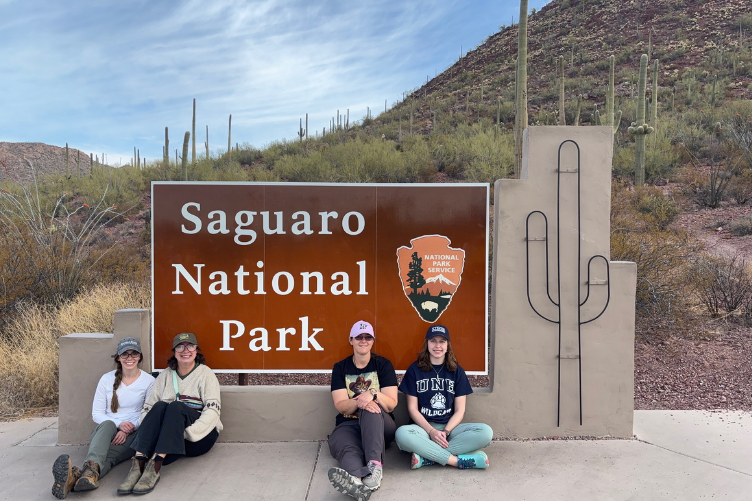 UNH graduate student Anna Frisbie (far right) and fellow researchers pose in front of entrance sign at Saguaro National Park in Arizona,