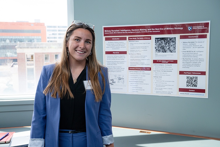 Woman in a blue blazer stands in front of a poster presentation