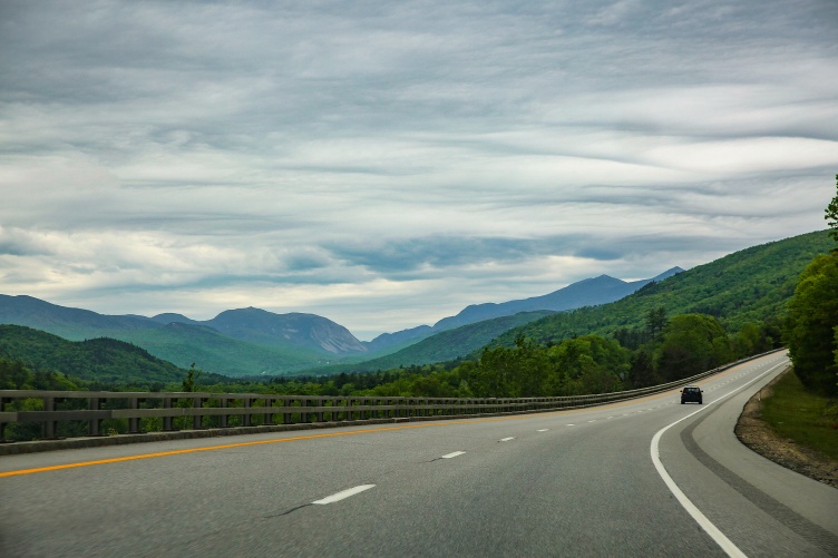 car driving on empty highway with mountains in backgroun
