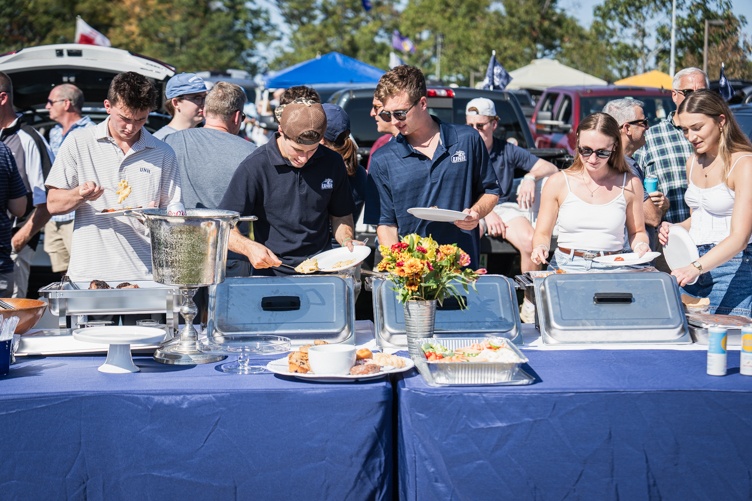 A line of people, many in UNH shirts, work through a buffet table