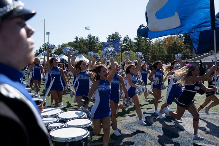 Members of the Wildcat cheer team run onto the field as the band plays