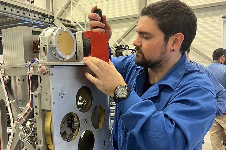 A student works on an electrical component for a rocket launch