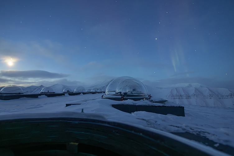 A glass bubble visible in front of snowy ground and a deep blue sky in the arctic