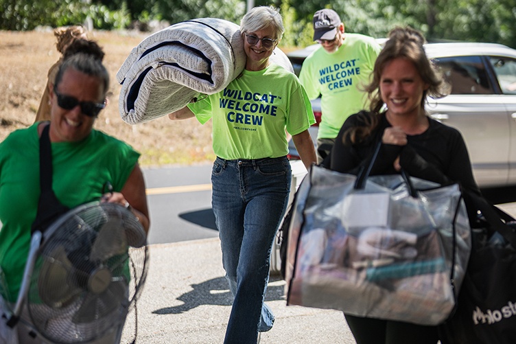 UNH President Elizabeth Chilton carries a mattress pad over her shoulder while helping students move in to their dorm room