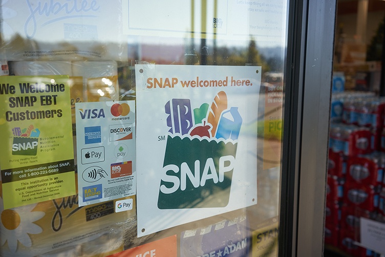 A window of a retail store displays a SNAP welcomed here sign