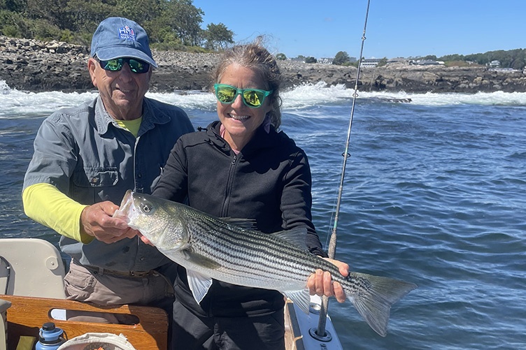Adrienne Kovach with large striped bass, fisherman Jim Smith