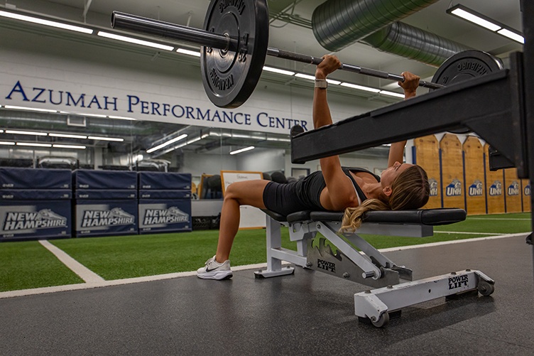 A woman lifts a bar with plates on it while bench pressing