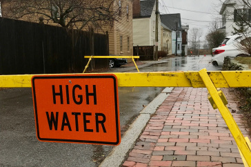 Flooded road blocked with yellow tape and "high water" sign