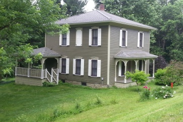 Grey house surrounded by green lawn.
