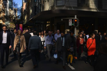 Women and men of different backgrounds cross a busy street in a city.