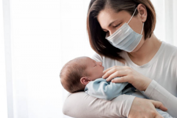 Women in mask holds a baby