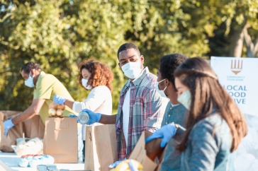 A photo showing a group of nonprofit workers filling food bags at a food drive.