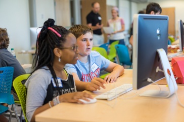 Two middle school students, a boy and a girl, work together on a computer.