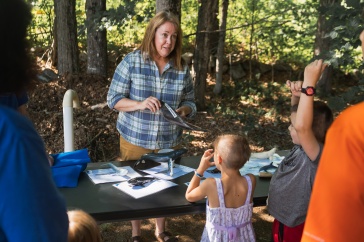 Woman in plaid shirt holds whale baleen so library patrons can see