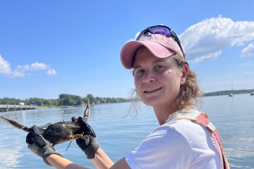 Female graduate student on a boat holding a male blue crab