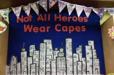 A library display with the words "Not All Heroes Wear Capes" showing a cityscape