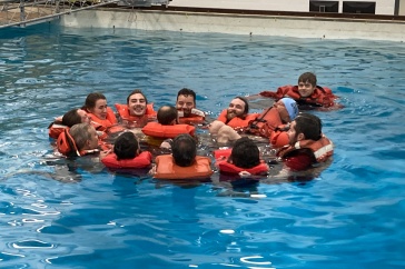 Group of people wearing lifejackets huddle in a circle in a pool