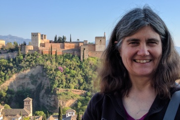 Lynn Kistler smiles in front of a medieval town. 