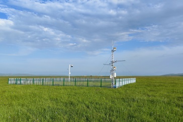 Scientific instruments sit in a green field below a blue sky.
