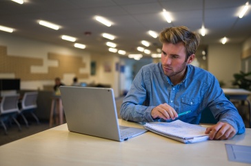 paul college online MBA looking at coursework on his laptop