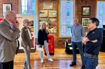 Three men and two women stand in the lobby of a Manchester mill building