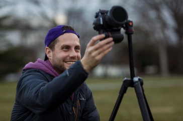 Assistant Professor Adam Brockett holds camera while taking a photo