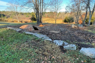 A stone foundation and brick structure are visible in a yard