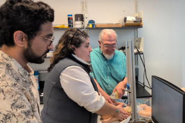 Prashant Purohit monitors data on the computer screen as Alyssa O’Brien, associate professor of nursing, and John LaCourse, electrical and computer engineering professor, practice CPR on a training mannequin that Purohit developed.
