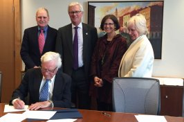 Jeffrey Sohl, director of UNH's Center for Venture Research;UNH President Mark Huddleston; UNH Provost Lisa MacFarlane; and Deborah Merrill-Sands, dean of the UNH's Paul College of Business and Economics; look on as Mel Rines '47 signs papers establishing a student angel investment fund in his name.