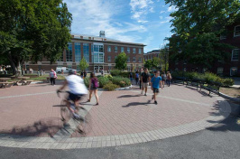 UNH students walking and biking through DeMeritt courtyard