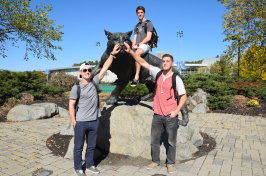 Three UNH students pose in front of the Wildcat statue. 