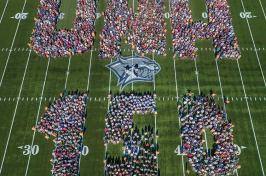 an aerial photo of UNH faculty, staff and students spelling out UNH 150 at Wildcat Stadium
