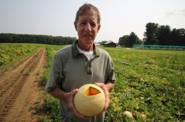 UNH professor emeritus of plant biology and genetics J. Brent Loy holding a cantaloupe in a field