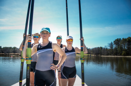 UNH rowers on a dock holding oars