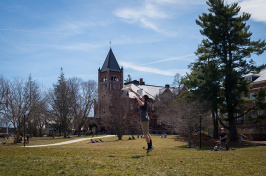 a student catching a frisbee in front of UNH's Thompson Hall