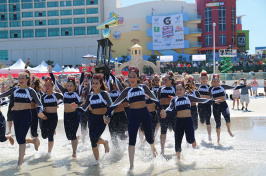 UNH cheerleaders running into the ocean with a trophy
