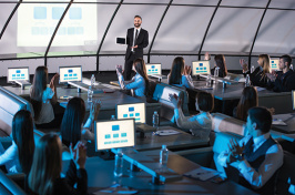 a man giving a presentation to a group of people at computers