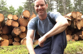 Greg Jordan in front of a log pile