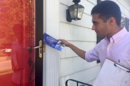 UNH Manchester student Hassan Essa putting a flyer in someone's door