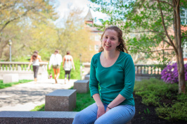 UNH's Allison Lehoux '18 sitting on a bench outside of James Hall at UNH