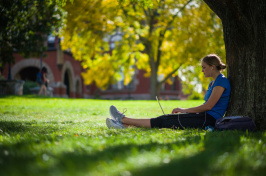 A UNH student sitting against a tree on the Durham campus