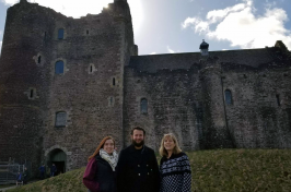 Two UNH students and a UNH alumna in front of a castle in Scotland 