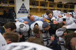 Coach Dick Umile and UNH hockey players in the locker room before a game