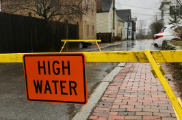 Flooded road blocked with yellow tape and "high water" sign