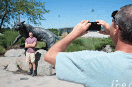 A parent takes a student's photo at the UNH Wildcat statue 