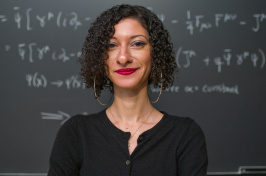 Chanda Prescod-Weinstein stands in front of a chalkboard with equations