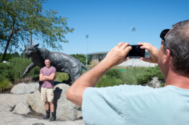 A UNH parent takes a photo of a student at the Wildcat statue 