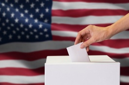 A hand putting a ballot into a ballot box