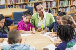 A group of students around a table with their teacher.