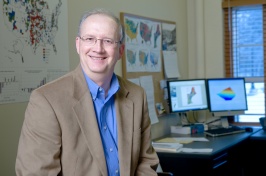 Photo of Ken Johnson in front of maps